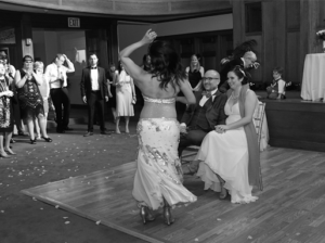 SharQui participant Suzanne at her wedding, where she hired Oreet to perform as a professional bellydancer. Oreet performs in a two piece bellydance costume in front of Suzanne and her husband, surrounded by party guests.